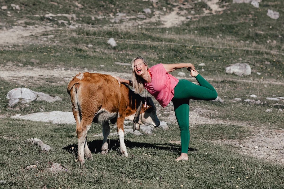 Michaela lehnt sich beim Yoga an eine junge Kuh