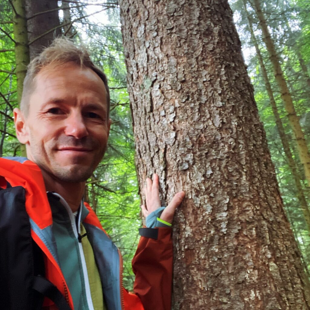 Matthias im Wald mit Hand am Baum